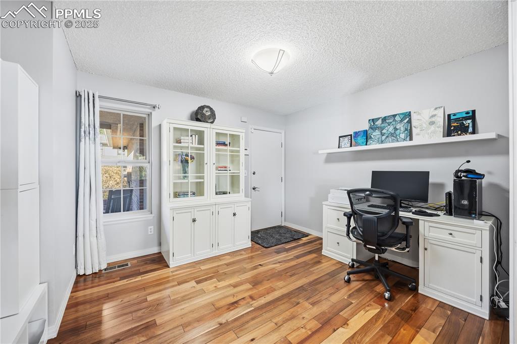 Image 13 of 50: Office with light wood-style flooring and a textured ceiling