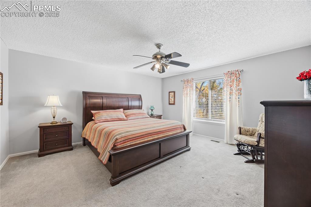 Image 19 of 50: Bedroom featuring light colored carpet, a textured ceiling, and ceiling fan