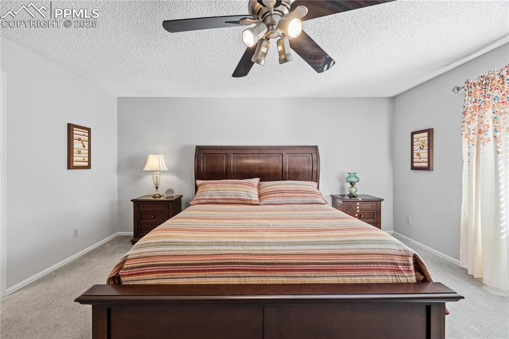 Image 20 of 50: Bedroom featuring light carpet, a textured ceiling, and ceiling fan