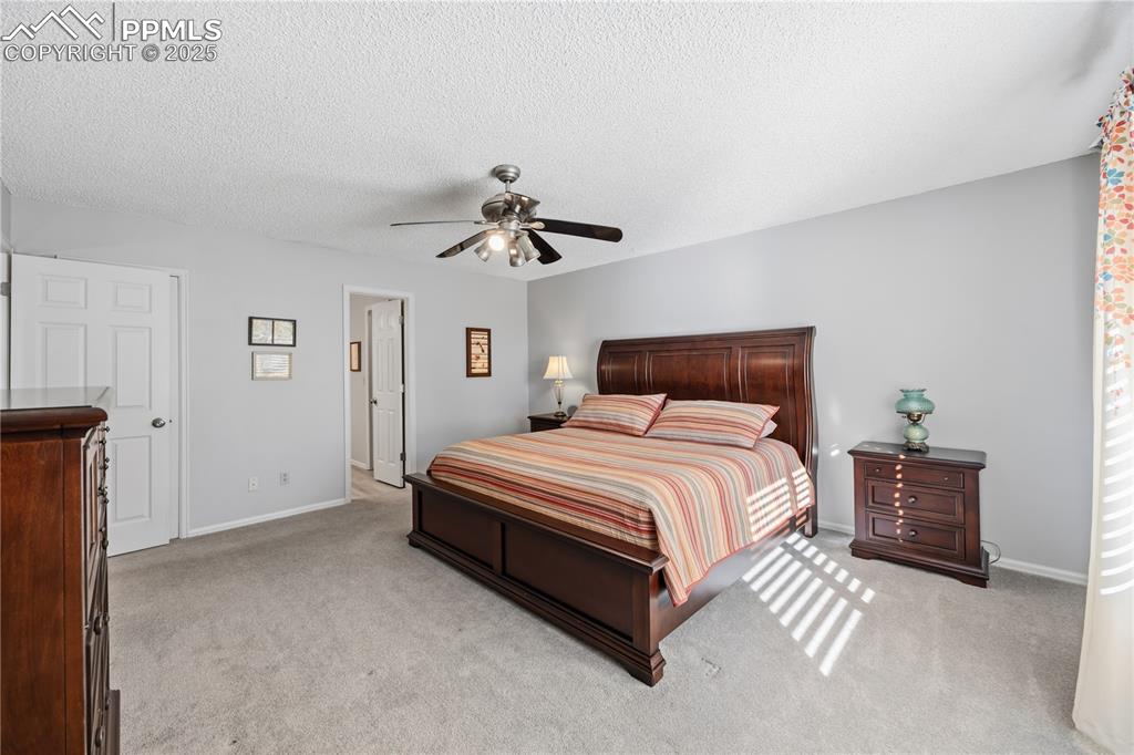 Image 21 of 50: Bedroom featuring light colored carpet, a textured ceiling, and a ceiling f