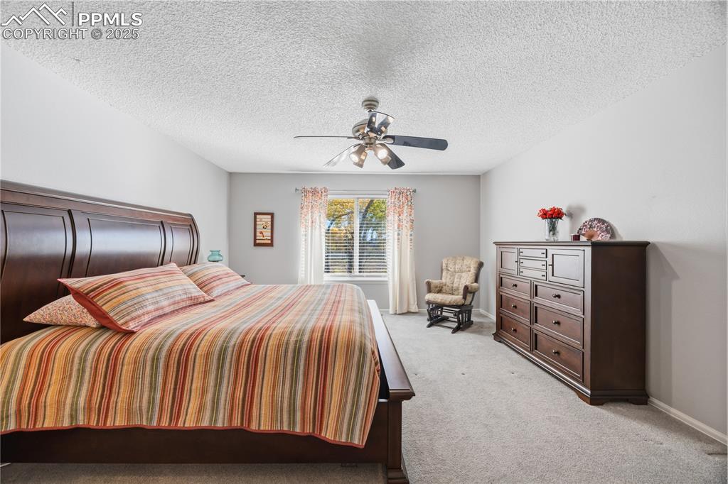 Image 22 of 50: Bedroom featuring carpet floors, a textured ceiling, and ceiling fan