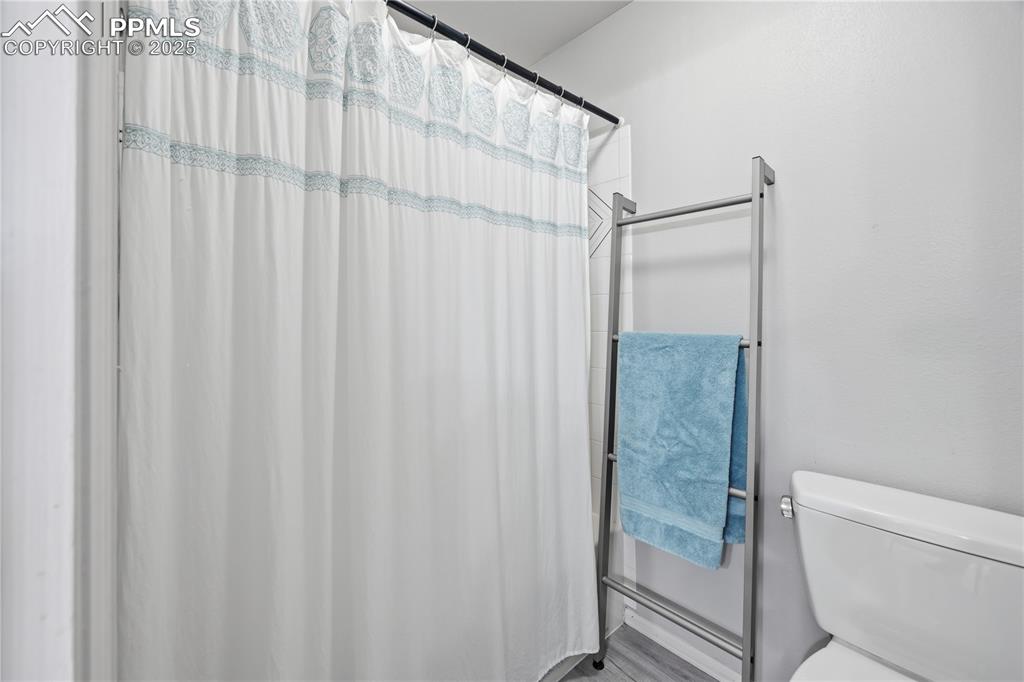 Image 25 of 50: Bathroom with a shower with shower curtain and toilet