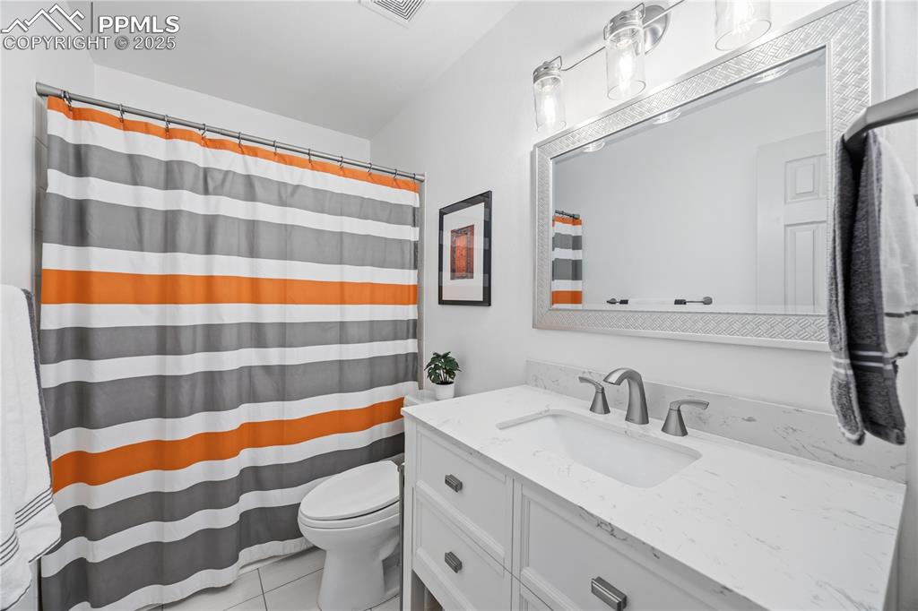Image 31 of 50: Full bath with curtained shower, vanity, and light tile patterned floors