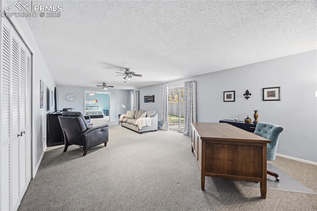 Image 34 of 50: Carpeted office space with a textured ceiling and a ceiling fan