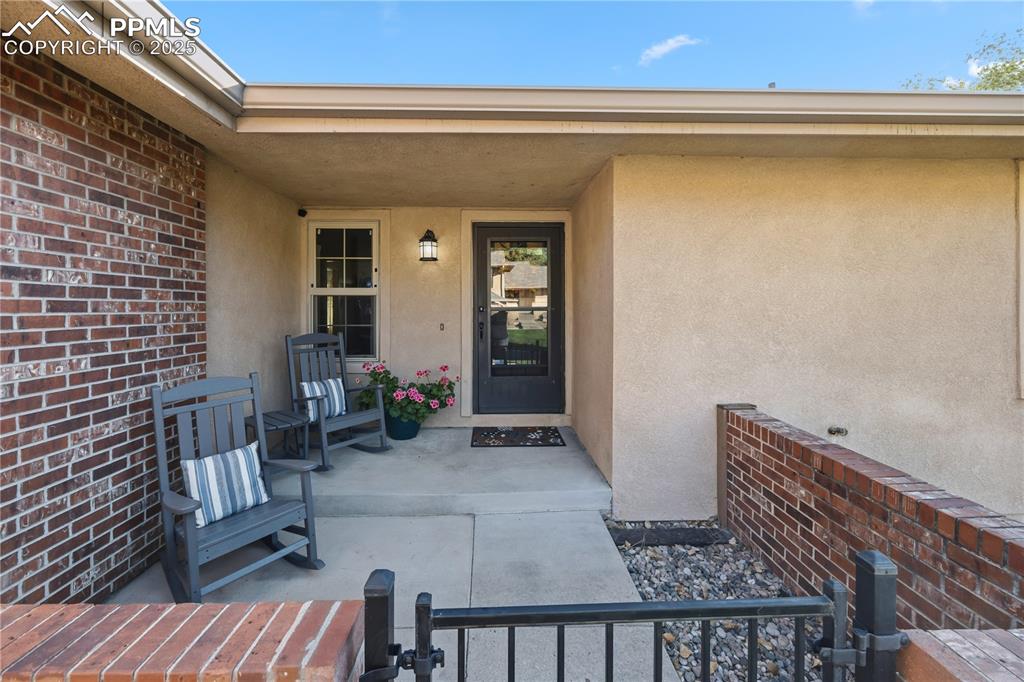 Image 4 of 50: Entrance to property featuring stucco siding, brick siding, and a porch