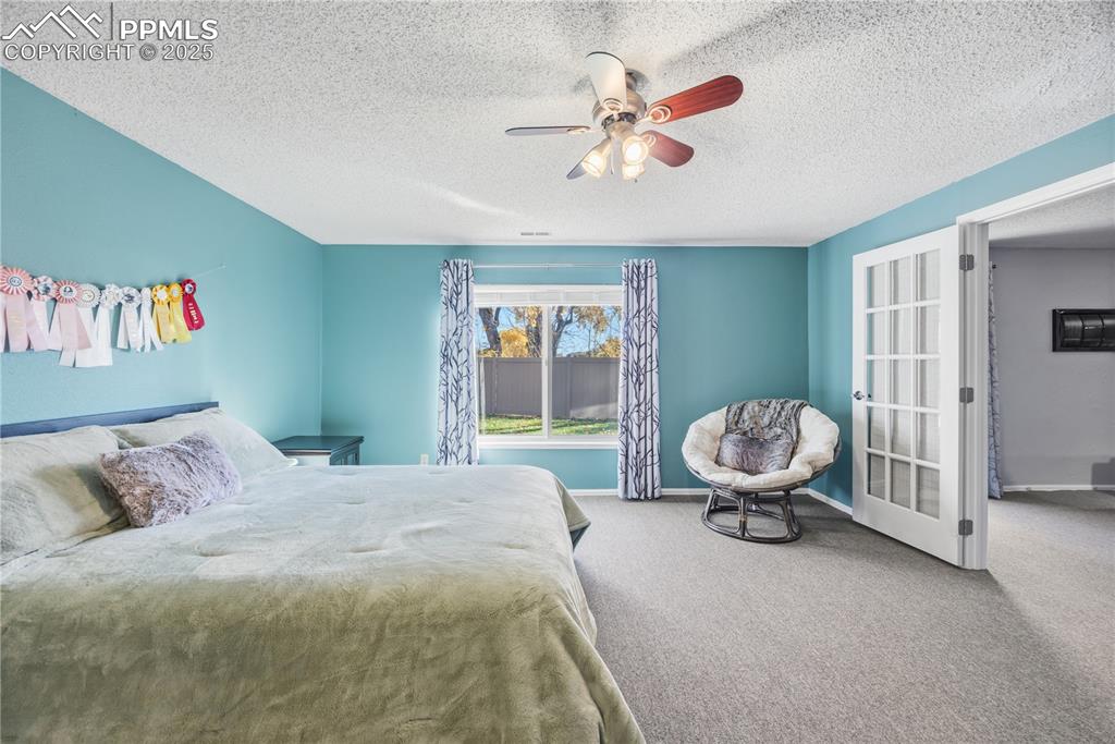 Image 41 of 50: Carpeted bedroom featuring a ceiling fan and a textured ceiling