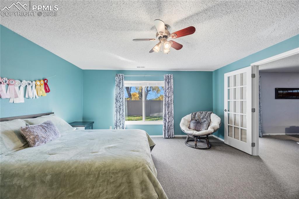 Image 42 of 50: Bedroom with carpet floors, a ceiling fan, and a textured ceiling