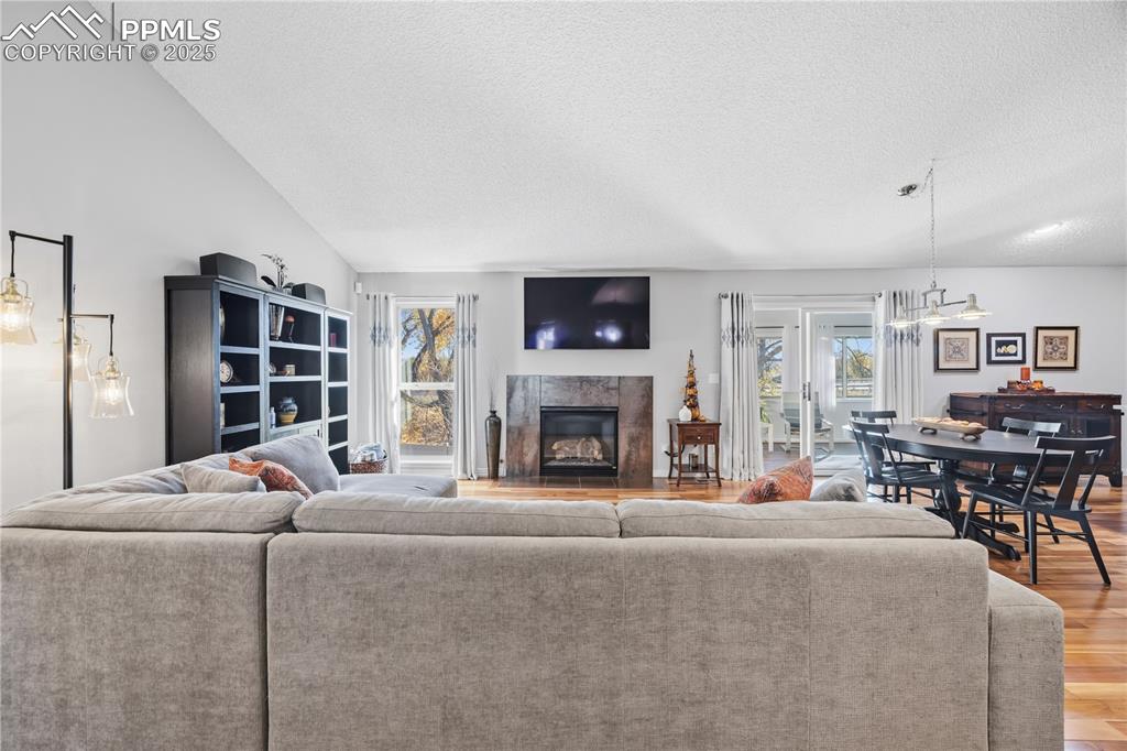 Image 8 of 50: Living room with a high end fireplace, wood finished floors, a textured cei