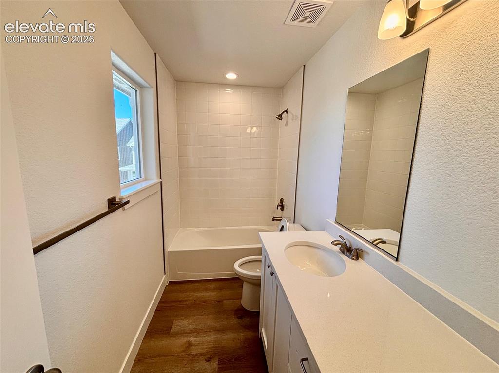 Image 10 of 17: White vanity with a single basin, light-toned countertop, and wood-finish f