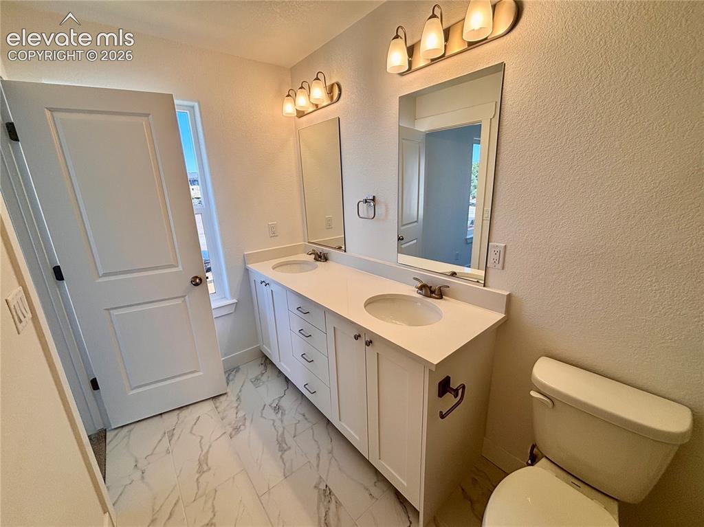 Image 14 of 17: Dual vanity with integrated sinks, white cabinetry, and a light-colored cou