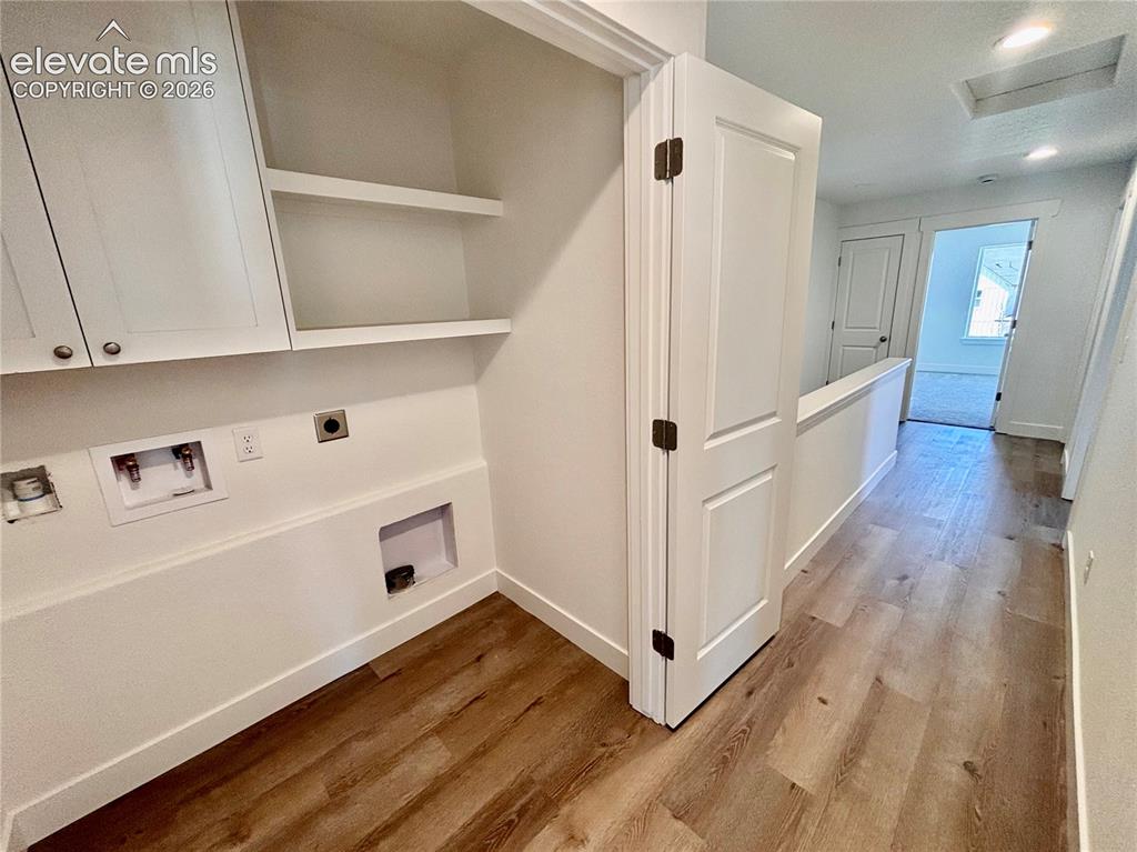 Image 15 of 17: Laundry area with built-in cabinetry, open shelving, and utility hookups