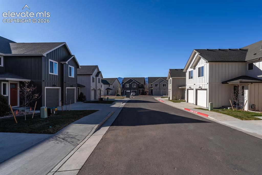 Image 3 of 17: Contemporary townhomes featuring vertical siding, attached garages, and pav