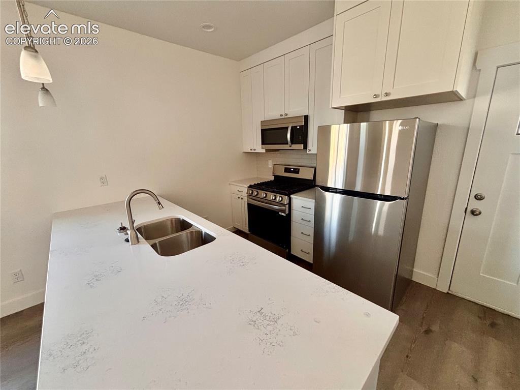 Image 5 of 17: Kitchen featuring white cabinetry, stainless steel appliances, a double bas