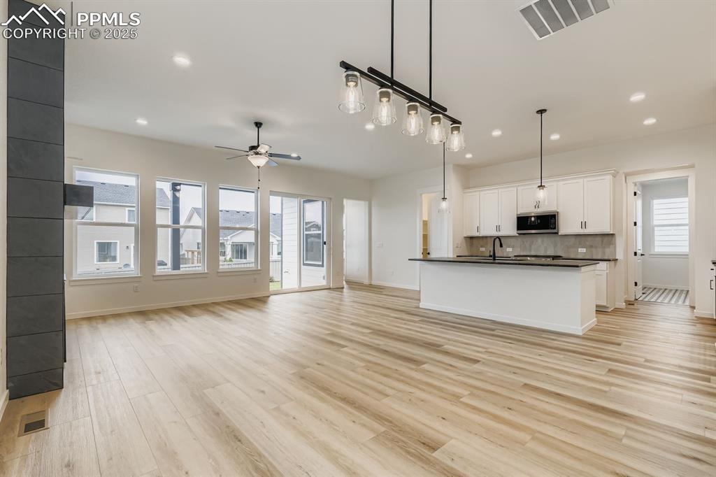 Image 10 of 28: Kitchen featuring open floor plan, hanging light fixtures, dark countertops