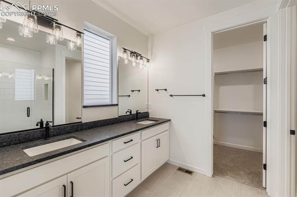 Image 13 of 28: Full bath featuring a spacious closet, a shower stall, double vanity, and p