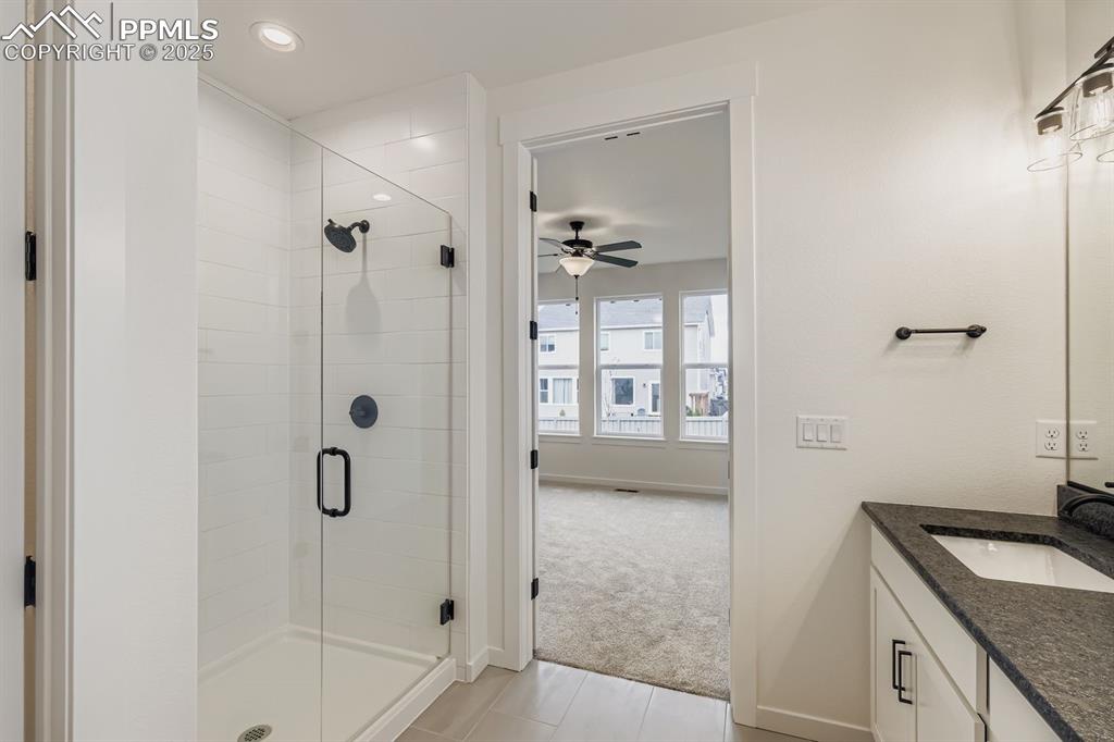 Image 14 of 28: Bathroom featuring a shower stall, vanity, light carpet, light tile pattern