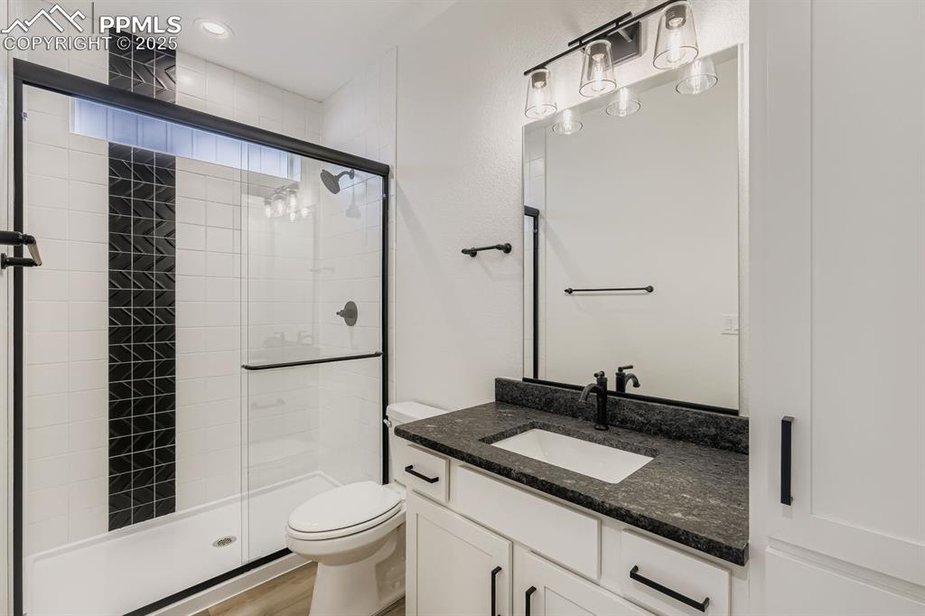 Image 17 of 28: Bathroom with a stall shower, vanity, and wood finished floors