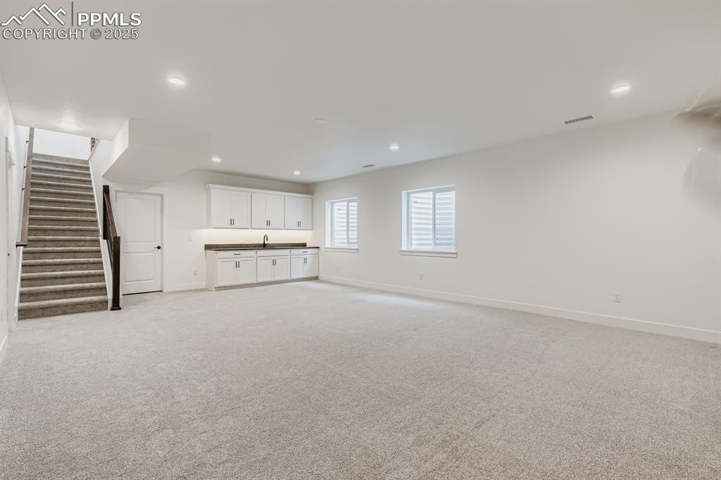 Image 19 of 28: Below grade area with stairway, light carpet, and recessed lighting