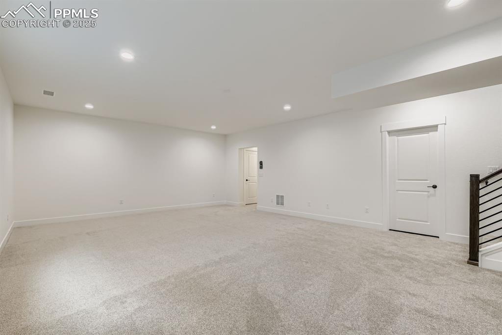 Image 20 of 28: Below grade area with recessed lighting, light carpet, and stairway