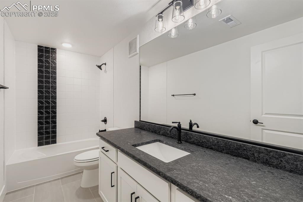 Image 24 of 28: Bathroom featuring vanity, washtub / shower combination, and light tile pat