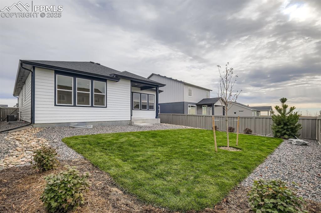 Image 28 of 28: Rear view of house with a fenced backyard and roof with shingles