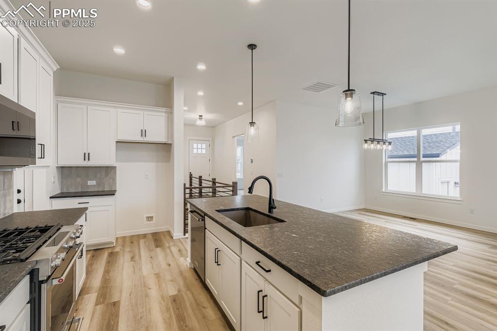 Image 8 of 28: Kitchen featuring stainless steel appliances, white cabinets, light wood fi
