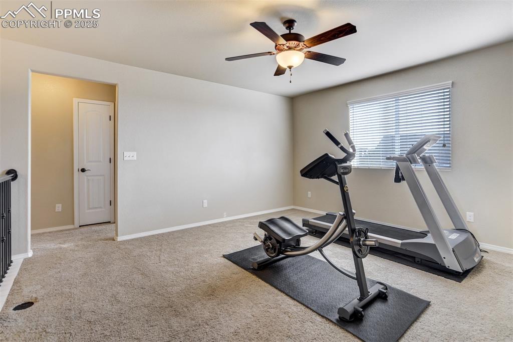 Image 25 of 50: Exercise room with carpet floors, baseboards, and a ceiling fan
