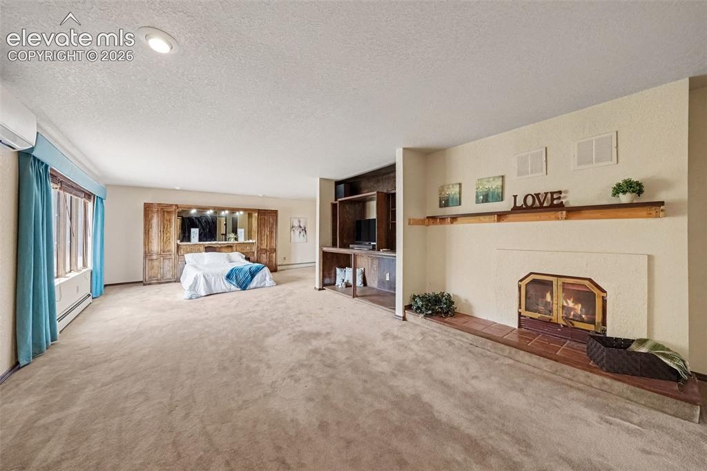Image 17 of 44: Spacious second primary bedroom upstairs features a cozy fireplace, private