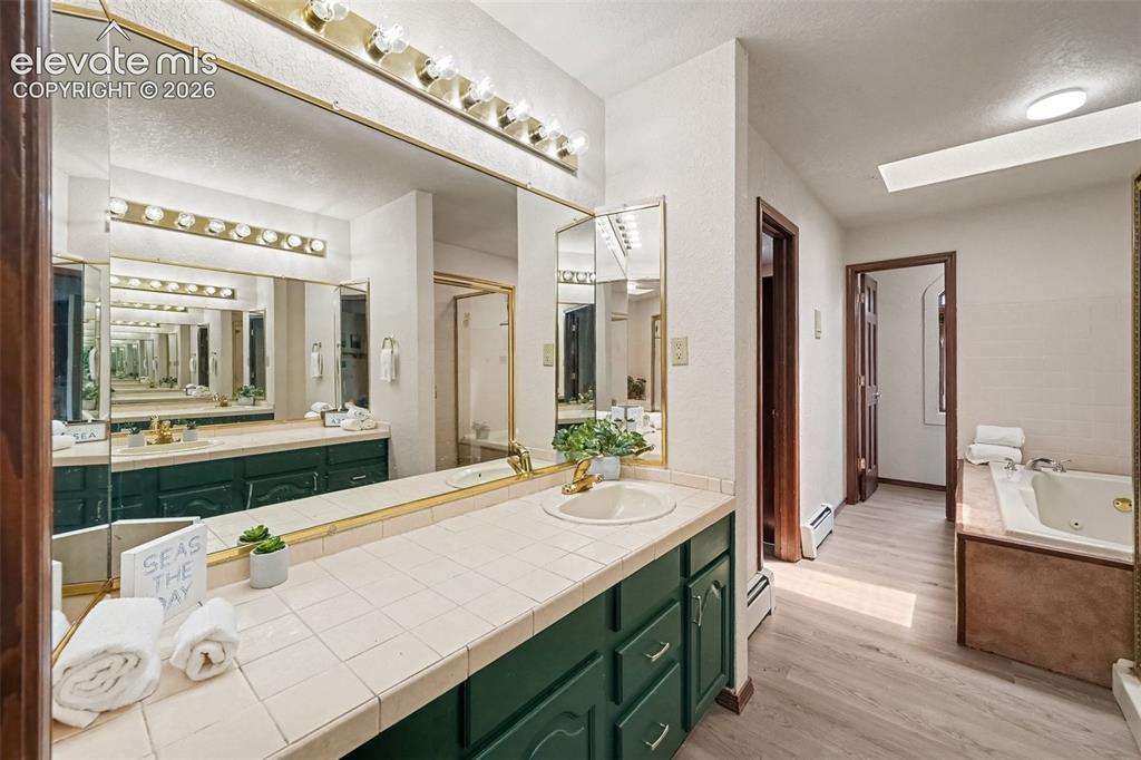 Image 20 of 44: Beautiful primary bathroom featuring dual vanities, a spacious standing sho