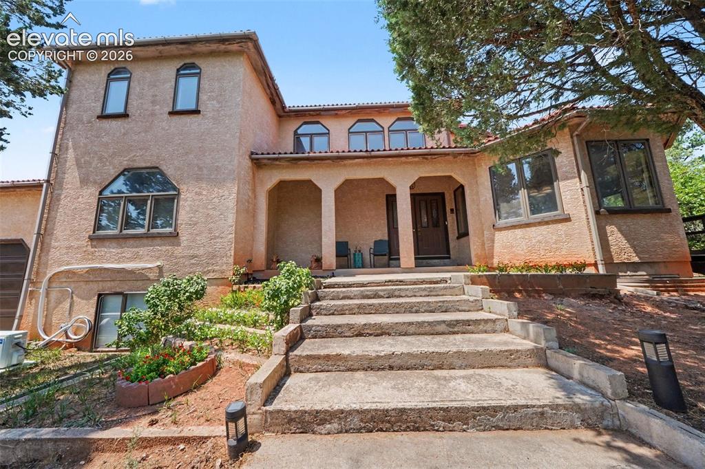 Image 3 of 44: A set of steps leads to the home, surrounded by established landscaping and