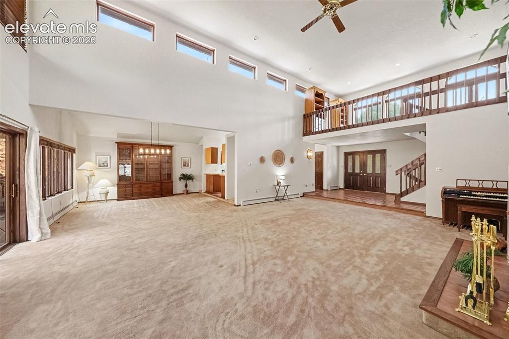 Image 4 of 44: Spacious living room featuring soaring ceilings, two ceiling fans, and a co