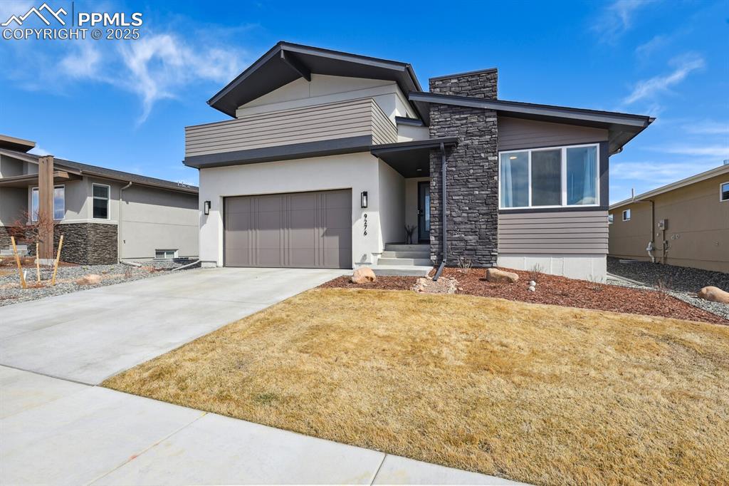 Image 2 of 41: Contemporary house featuring stone siding, stucco siding, an attached garag