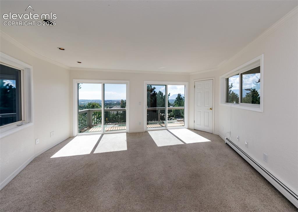 Image 26 of 50: Large office on main level with 2 sliding glass doors to upper deck