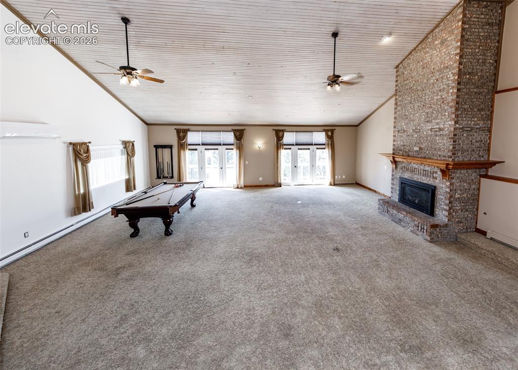 Image 7 of 50: Living room with fireplace and two sliding doors to the upper outside deck