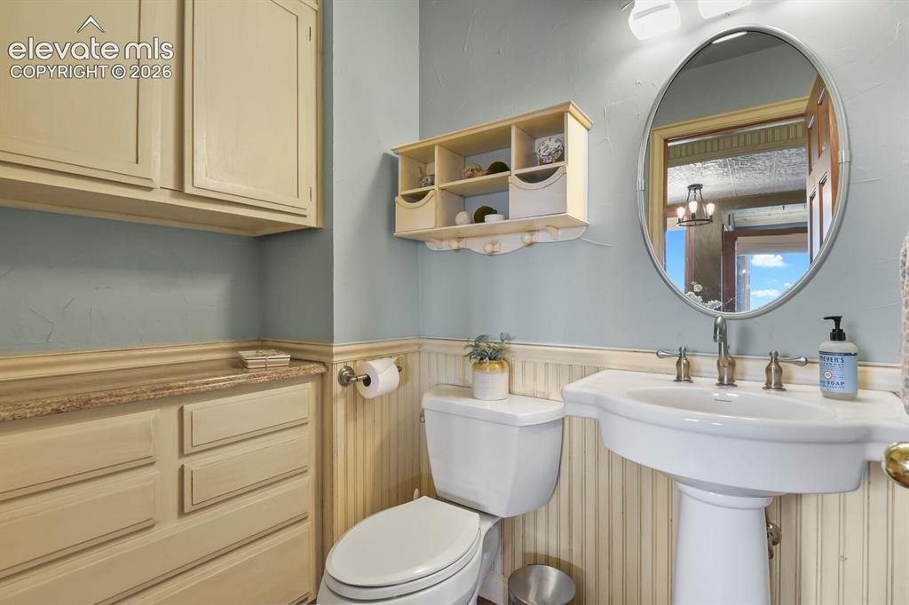 Image 19 of 41: Charming powder room with pedestal sink, beadboard detail, and a clean, inv