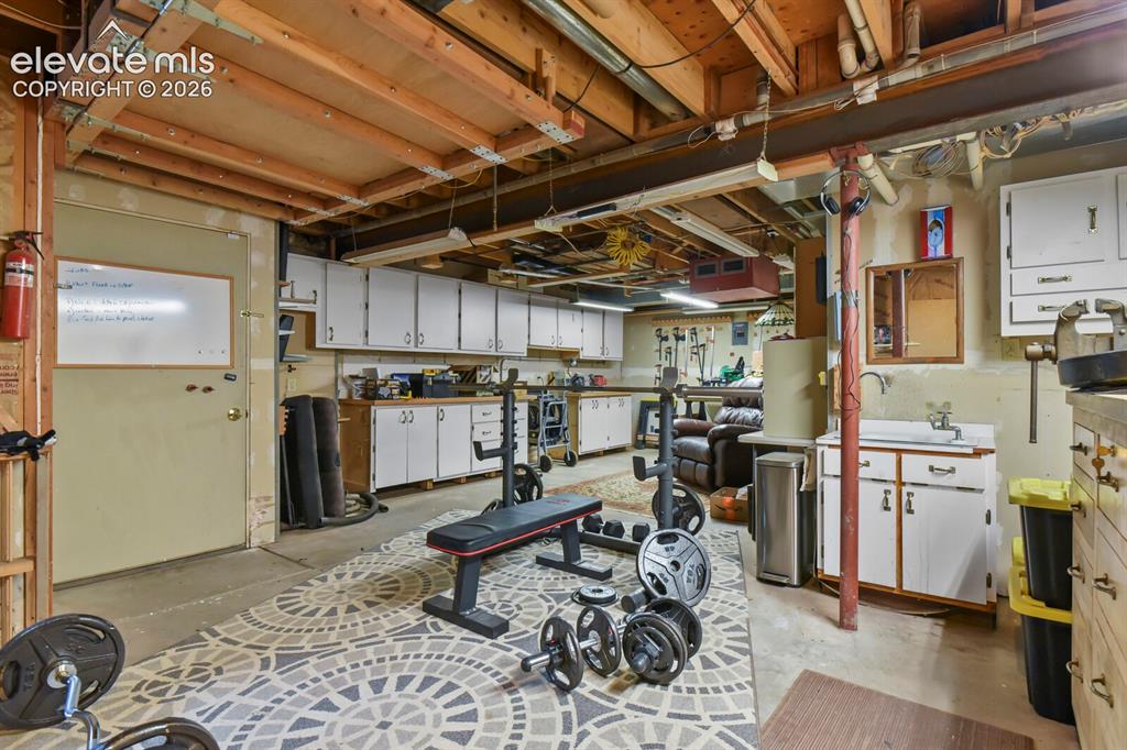 Image 33 of 41: Expansive workshop with built-in cabinetry, utility sink, and direct access