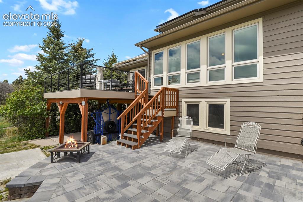 Image 34 of 41: Brand new lower stone patio, new upper deck, and a covered patio from the w