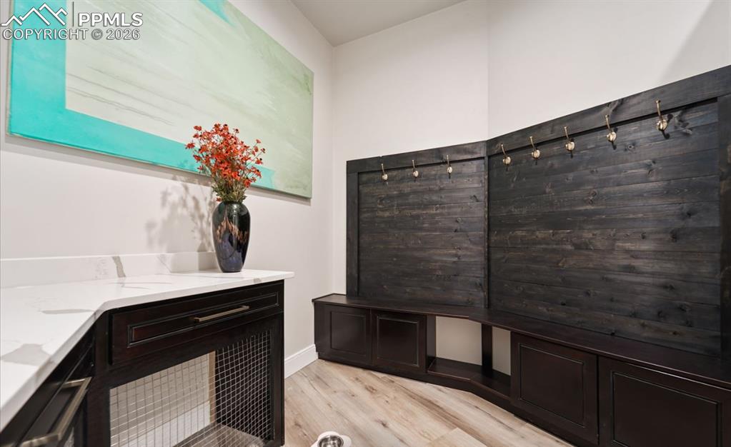 Image 27 of 50: Between the garage and kitchen, this mudroom provides shoe and coat racks, 