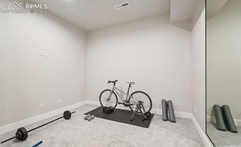 Image 33 of 50: This dedicated exercise room has a mirrored wall, and French door access.