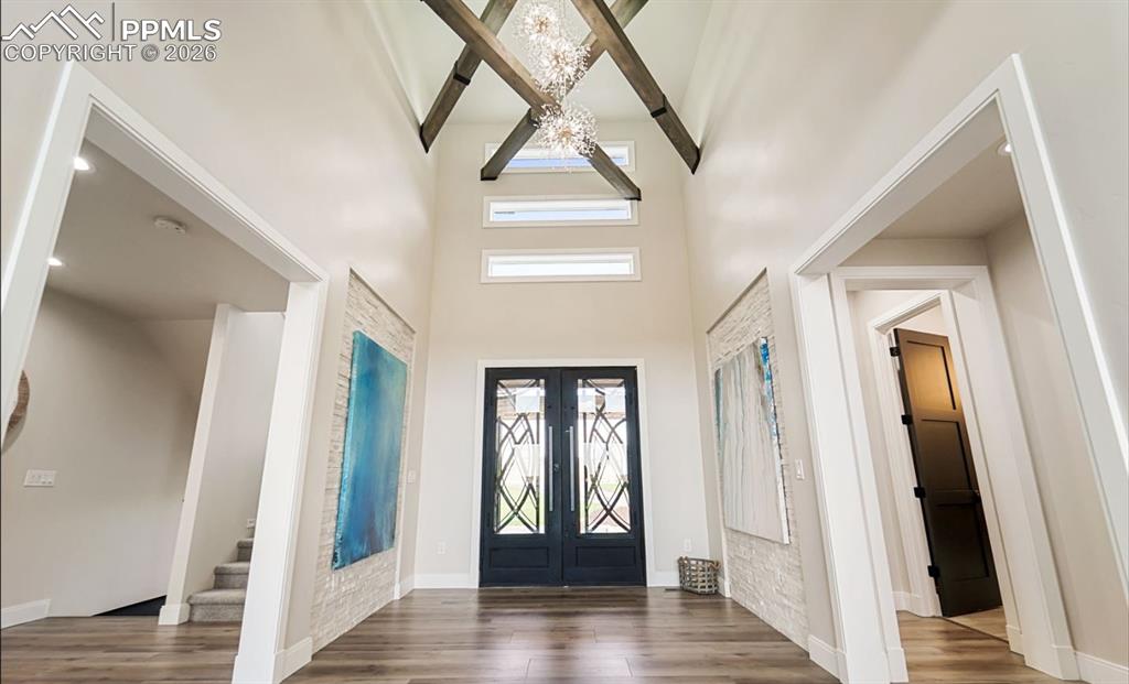 Image 5 of 50: Foyer features custom metal doors with opening glass for air flow, and an i