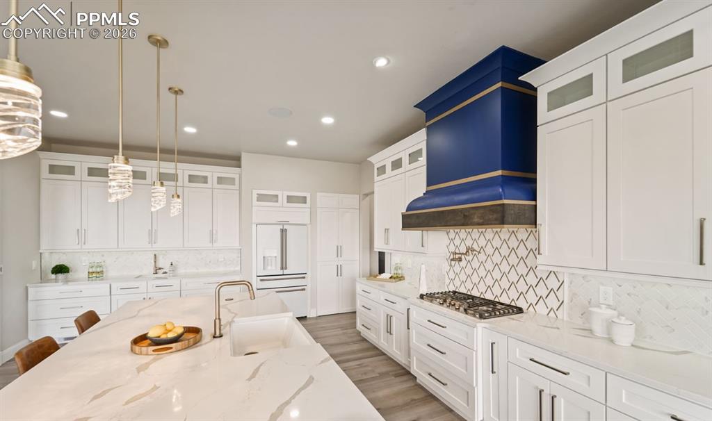 Image 9 of 50: Professional grade gas cooktop hosts pot filler and stunning hood.