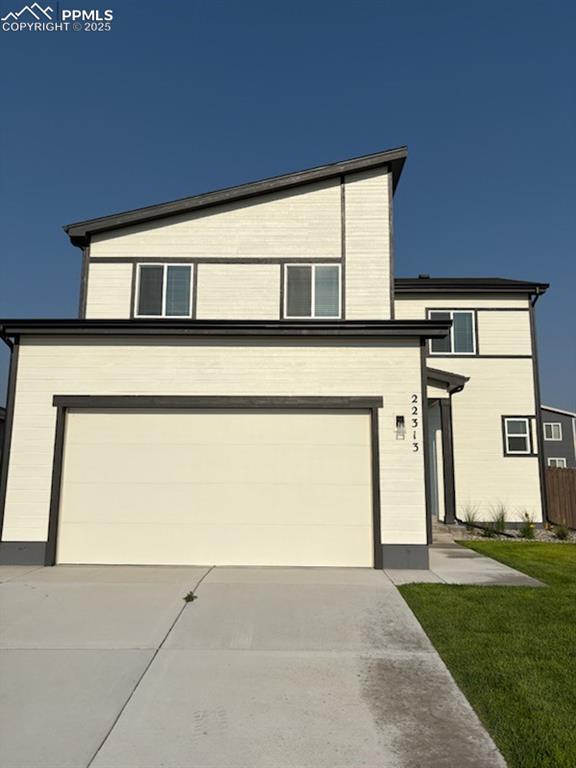 Caption: Contemporary home featuring concrete driveway and a garage