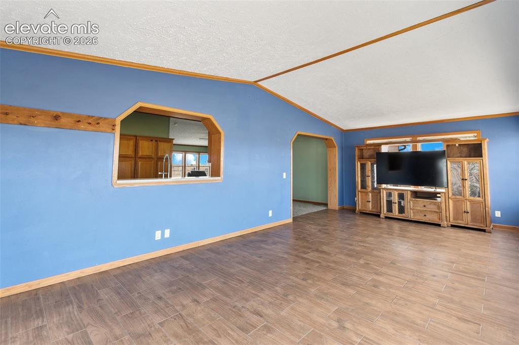 Image 13 of 45: Spacious living area featuring wood-finish flooring, vaulted ceilings, and