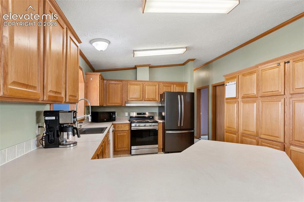 Image 20 of 45: Kitchen featuring extensive wood cabinetry, light-toned countertops, and a
