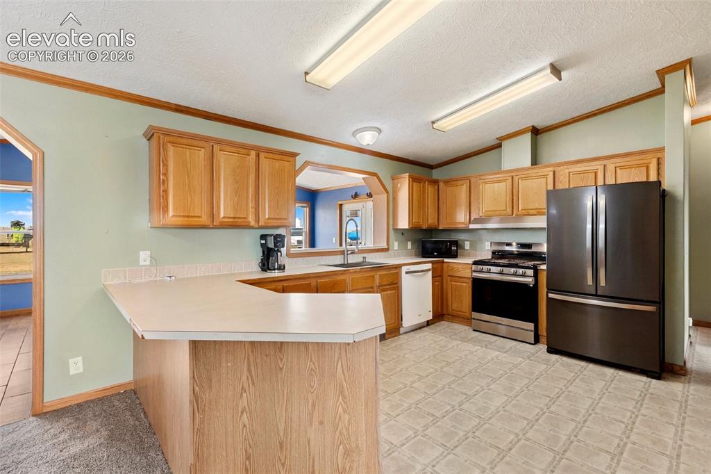Image 21 of 45: Kitchen featuring wood-finish cabinetry, a breakfast bar, and a stainless s