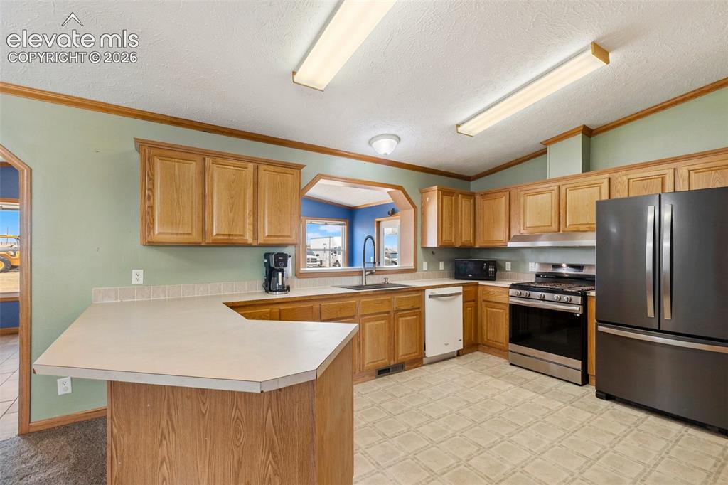 Image 22 of 45: Kitchen featuring wood-finish cabinetry, a peninsula with a countertop, sta