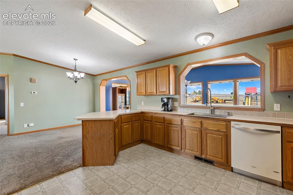 Image 23 of 45: Kitchen with wood-finish cabinetry, a stainless steel sink, and a white dis
