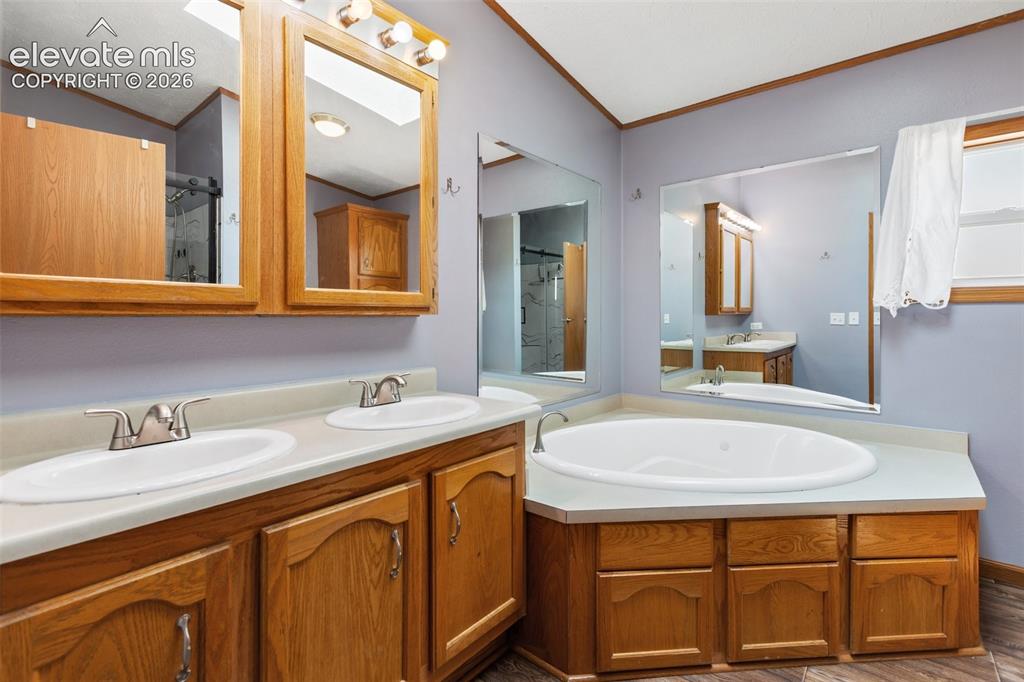 Image 31 of 45: Spacious bathroom featuring a built-in corner soaking tub, a dual vanity wi