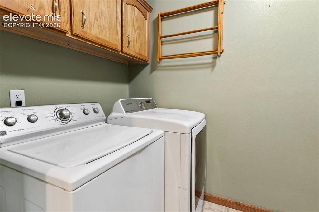 Image 33 of 45: Dedicated utility space featuring overhead wood cabinetry and light green p