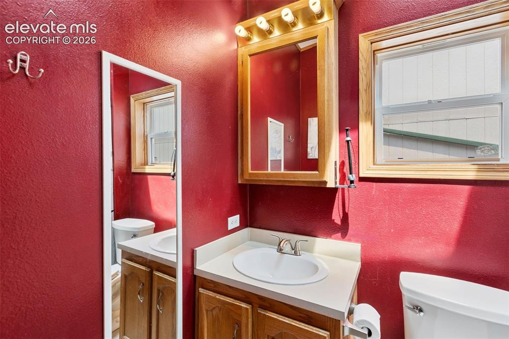 Image 34 of 45: Bathroom featuring a wood-finish vanity with a white oval sink and chrome f